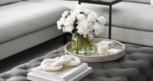 A large black leather tufted ottoman coffee table sits on a light .